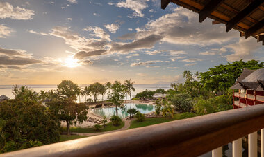 Blick vom Balkon auf den tropischen Garten, den Pool und das Meer